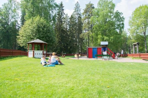 a woman and two children sitting on the grass in a park at First Camp Mellsta-Borlänge in Borlänge