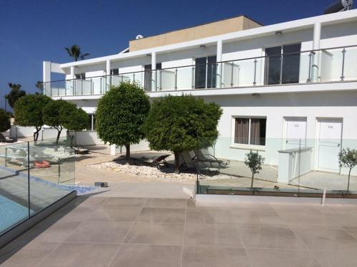 a large white building with trees and a swimming pool at Fedrania Gardens Hotel in Ayia Napa