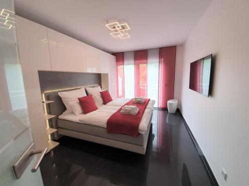 Schlafzimmer mit einem Bett mit roten und weißen Kissen in der Unterkunft Ihr Ticket ins Grüne - Topmoderne 5-Sterne-Ferienwohnung in Bad Kreuznach