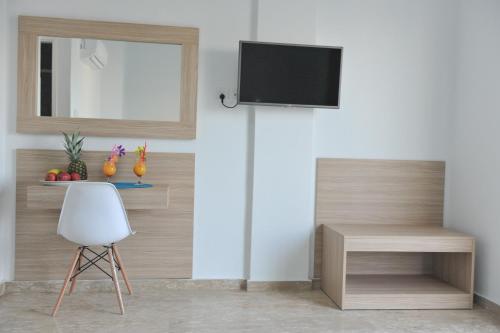 a room with a chair and a television on a wall at Fedrania Gardens Hotel in Ayia Napa