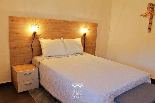 a bedroom with a bed with two lights on the wall at Refúgio do Alva - Serra da Estrela in Seia