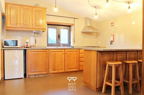 a kitchen with wooden cabinets and a counter top at Refúgio do Alva - Serra da Estrela in Seia