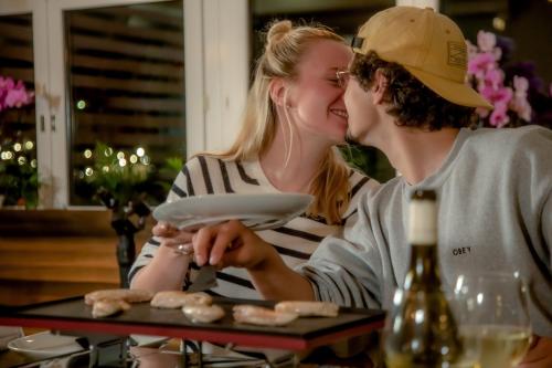 a woman kissing a man while sitting at a table at GRAND your home with common kitchens with self check-in in Engelberg