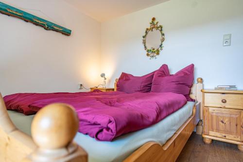 a bedroom with a bed with purple sheets and a mirror at Fischerhus Ummanz FW2 in Ummanz