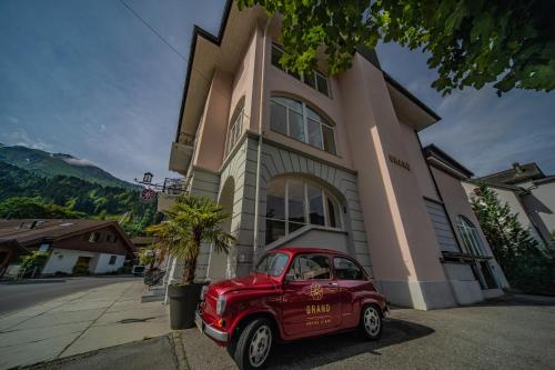 a red car parked in front of a building at GRAND your home with common kitchens with self check-in in Engelberg