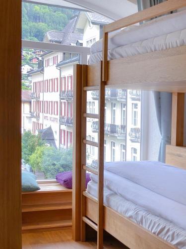 a bedroom with bunk beds and a large window at GRAND your home with common kitchens with self check-in in Engelberg