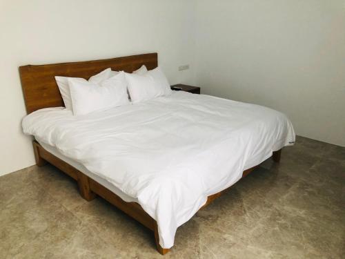 a large white bed with white sheets and pillows at 隱山行旅包棟民宿 in Puli