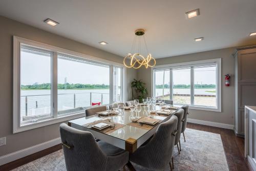 a dining room with a table and chairs and windows at Lago-mar Luxury Modern Waterfront Home in Atlantic City