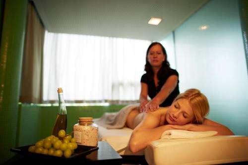 a woman laying on a bed next to a table at LOISIUM Wine & Spa Hotel Langenlois in Langenlois