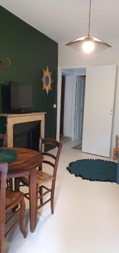 a living room with a table and chairs and a television at La ferme du chateau in Puygiron