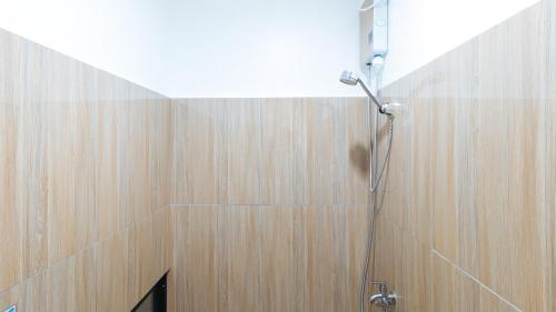 a shower in a bathroom with a wooden wall at RedDoorz @ DBuilders Ph1 Taguig in Manila