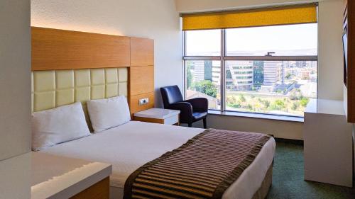 ein Hotelzimmer mit einem Bett, einem Stuhl und einem Fenster in der Unterkunft Nüzhet Hotel in Kayseri