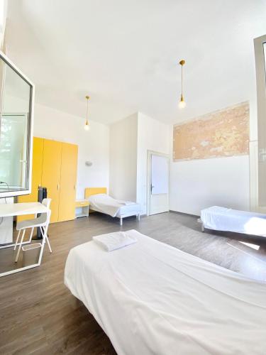 a room with two beds and a table and a desk at BRIBANO HOSTEL & bike sharing-workers and tourists hospitality in Sedico