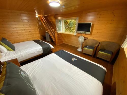 a bedroom with two beds and a tv in a cabin at Lala Maple Villa in Hualing