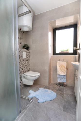 a bathroom with a toilet and a sink and a window at Studio apartman Mihaella in Kaštela
