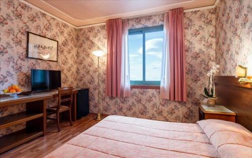 モンテカティーニ・テルメにあるAlbergo Santa Barbaraのベッドと机と窓のある寝室