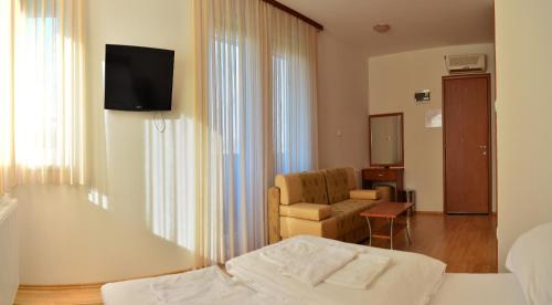 a hotel room with a bed and a chair and a television at Rooms Funda Lepoglava in Ivanec