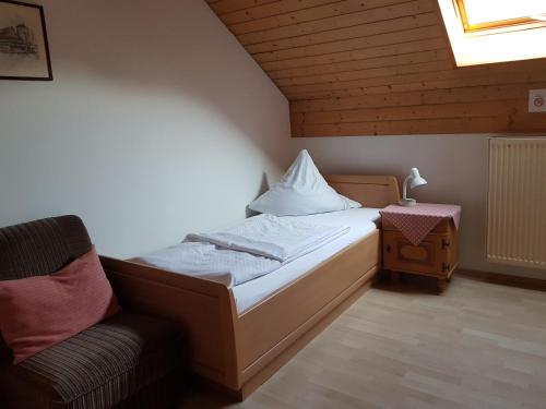 a small bedroom with a bed and a chair at Duschlwirt in Ampfing