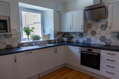 a kitchen with white cabinets and a window at Airds Apartments in Oban
