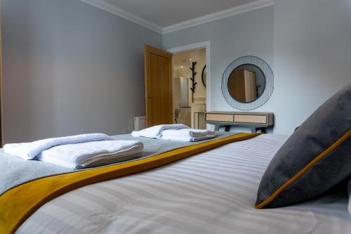 a bedroom with a bed with two pillows and a mirror at Airds Apartments in Oban