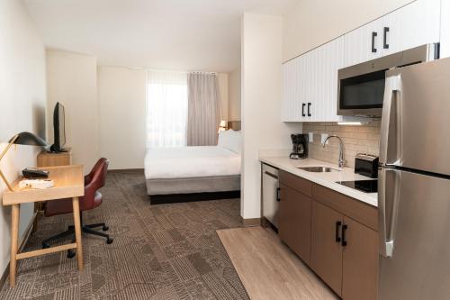 a kitchen with a refrigerator and a desk with a bed at Staybridge Suites Nashville - Vanderbilt Area by IHG in Nashville