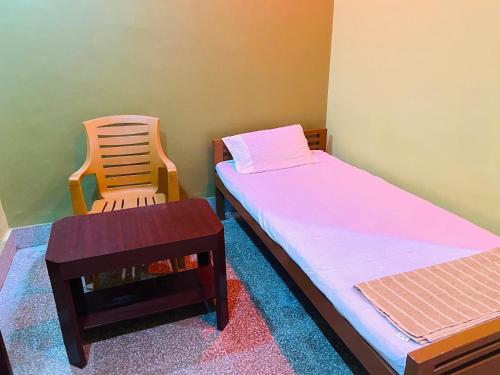 a small room with a bed and a chair at Hotel Nishi Pvt ltd in Balasore