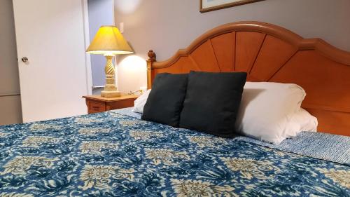 a bed with a blue and white blanket and a lamp at Aruba Cunucu Residence in Palm-Eagle Beach