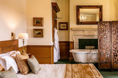 a bedroom with a bath tub and a bed and a fireplace at Ednam House Hotel in Kelso