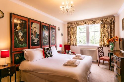 een slaapkamer met een groot bed en een kroonluchter bij Ednam House Hotel in Kelso