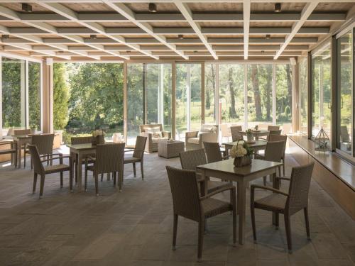 a restaurant with tables and chairs and windows at Corte San Ruffillo Country Resort in Dovadola
