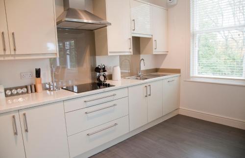 a kitchen with white cabinets and a sink and a window at Valley View in Harrogate
