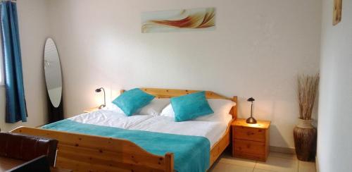a bedroom with a wooden bed with blue pillows at Hôtel-Gîte rural à 3 km de Delémont in Courcelon