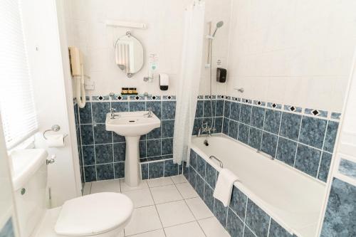a bathroom with a sink and a tub and a toilet at The Pier Hotel in Eastbourne