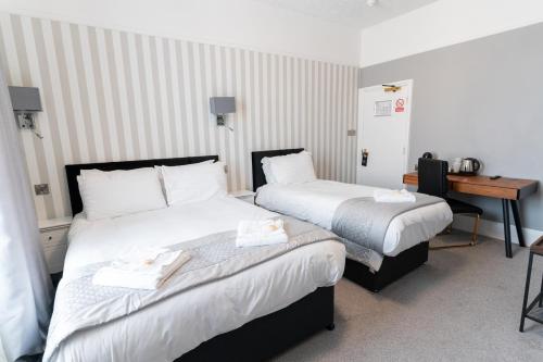 a hotel room with two beds and a desk at The Pier Hotel in Eastbourne
