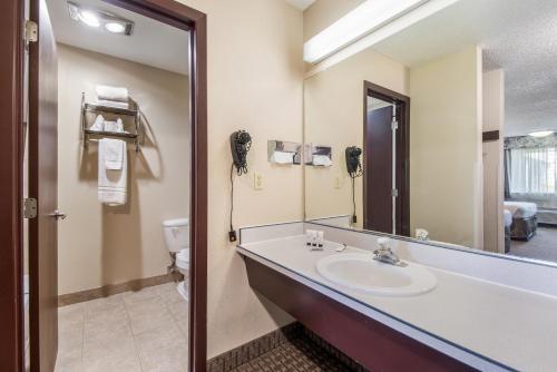 W łazience znajduje się umywalka, toaleta i lustro. w obiekcie Red Lion Inn & Suites Vancouver w mieście Vancouver
