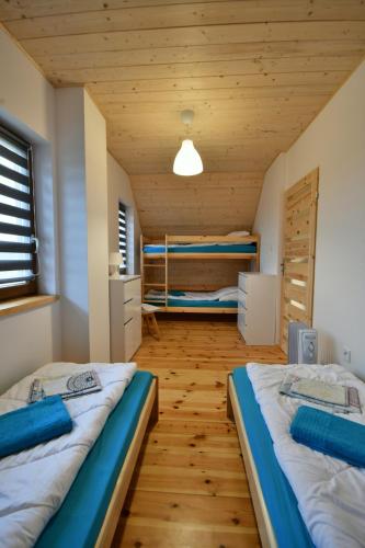 two beds in a room with wooden ceilings at Słowińskie Widoki domki Flora, Fauna, noclegi Smołdziński Las in Smołdziński Las