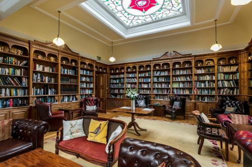 a library with leather chairs and bookshelves and a window at Doxford Hall Hotel And Spa in Chathill