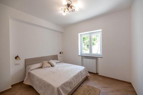 a white bedroom with a bed and a window at Casa Antonia in Anacapri