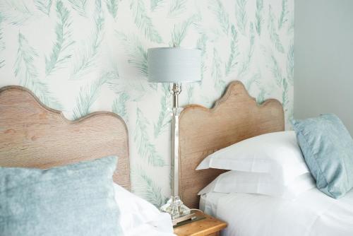 a bedroom with a bed with a lamp and a tropical wallpaper at The Cheney Arms in Gaddesby