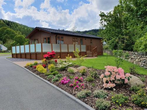 a house with a flower garden in front of it at Llyn Alwen Lodge Snowdonia National Park in Betws-y-coed