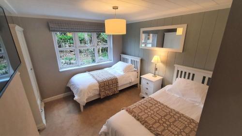 a small bedroom with two beds and two windows at Llyn Alwen Lodge Snowdonia National Park in Betws-y-coed