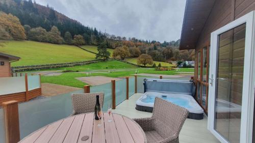a balcony with a table and chairs and a hot tub at Llyn Alwen Lodge Snowdonia National Park in Betws-y-coed