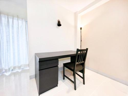 a black desk with a chair next to a window at Grand Residence in Bangkok