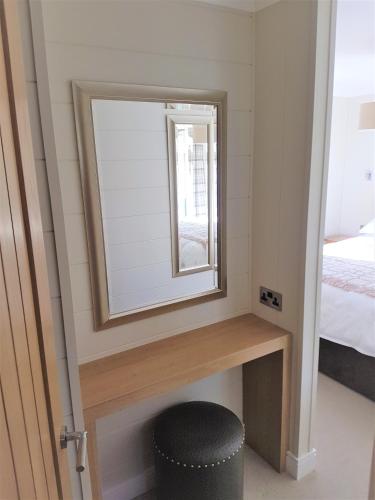 a mirror and a stool in a room with a bed at Llyn Brenig Lodge in Betws-y-coed