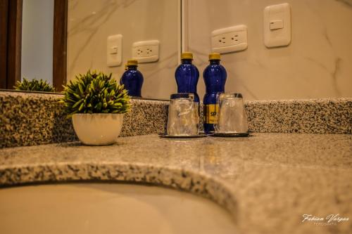 three blue bottles sitting on a counter with a potted plant at Adamas House Hotel Boutique in Quito