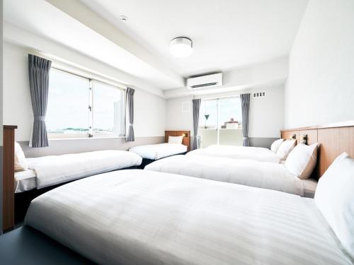 three beds in a room with windows at Rakuten STAY Naha Yachimun Street - standard 6 Bed Room in Naha