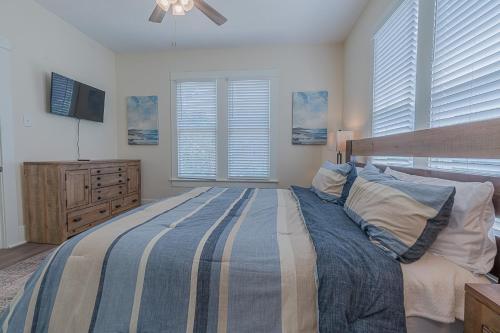 a bedroom with a bed and a tv and windows at Uptown Cottage Newly Updated Home Near the Strand Galveston Harbor and UTMB in Galveston