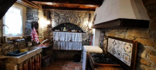 a stone kitchen with a stove and a stone wall at la corte dei cerri in Spervara