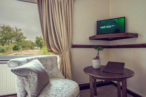 a living room with a chair and a table with a tv at Ardagh Hotel & Restaurant in Clifden