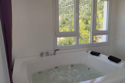 a white bath tub in a bathroom with two windows at muda apart kalkan in Kalkan